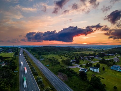 A drone view of the Port Hope streets surrounded by buildings and nature during a colorful sunset