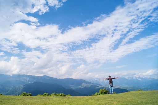 A man in the field of Kashmir Mountain under a beautiful blue cloudy sky