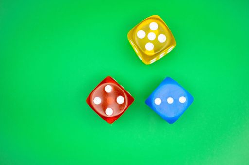 A top view of yellow, red, and blue dice on a green surface