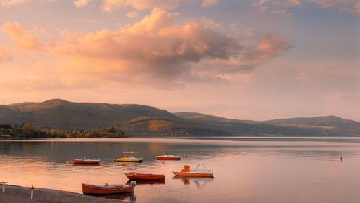 A small boats in a beautiful lake under cloudy sky during sunset time