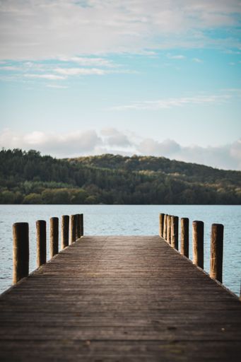 A vertical shot of a wooden jetty on Lake District in Cumbria, United Kingdom