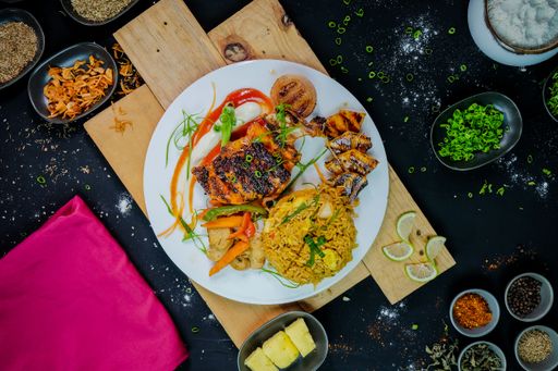 A vertical shot of grilled fish with vegetables and rice served on a plate