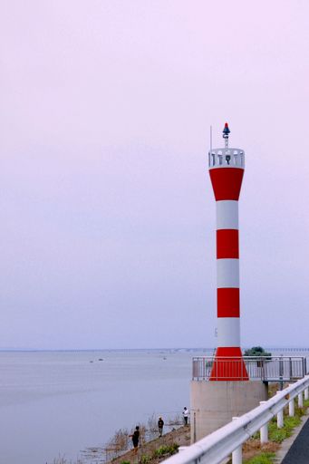 A vertical shot of a tranquil sea with a lighthouse on the shore against a beautiful sky