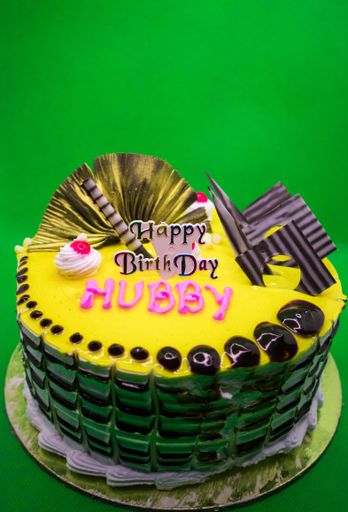 A birthday cake with chocolate toppings and yellow background ready to cut