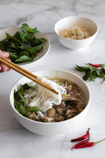 A vertical shot of Vietnamese food with sticks and with red chilies on the table
