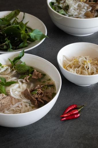 A vertical shot of Vietnamese meal, soup Pho Bo with chilies on the side