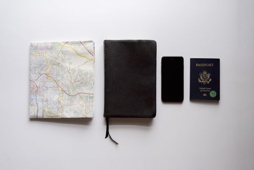 An overhead shot of a book in the middle of smartphone, passport and a map - concept traveling