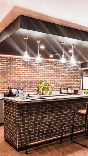 A vertical shot of a beautiful modern brick kitchen interior with hanging illuminated lights