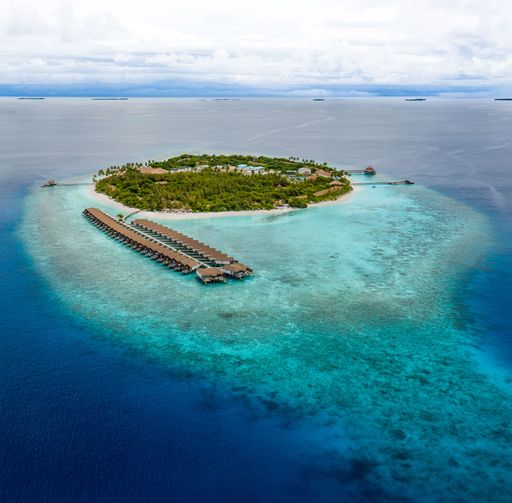 An aerial view of a tropical island with a dock in the water in the Maldives