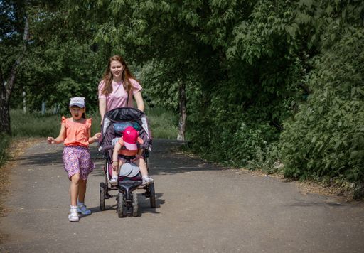 A close up of a mother with her daughters walking in a park