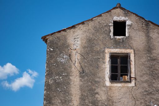 A closeup shot of an old, abandoned house with blue sky in the background