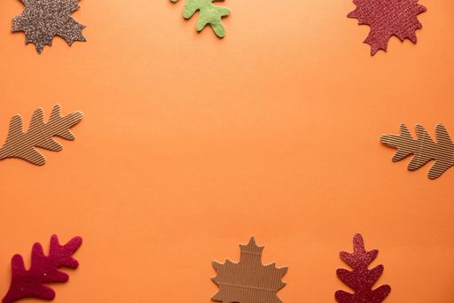 An overhead shot of cut out leaves over an orange surface great for background or writing text