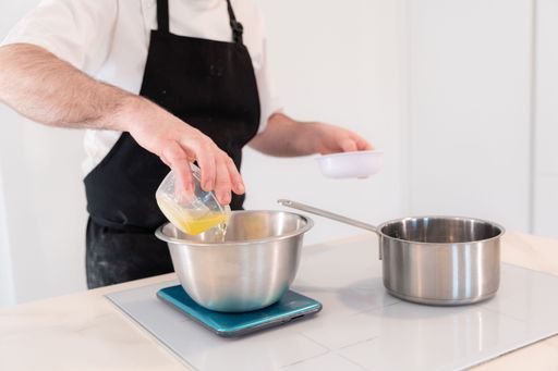 Hands of a man cooking a red velvet cake at home, preparing Swiss meringue with egg whites in a bain-marie, work in the kitchen at home