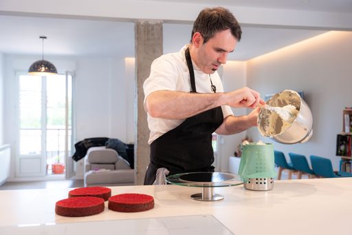 A man cooking a red velvet cake at home, pouring the cream in the piping bag
