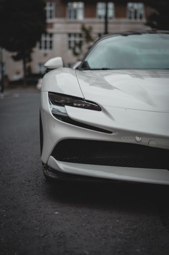 A vertical shot of a white Ferrari SF90 Stradale seen cruising the streets of London