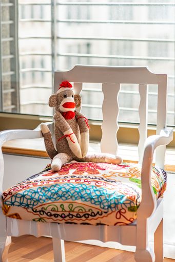 A vertical shot of a stuffed toy monkey on a colorful chair