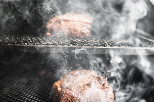A closeup shot of meat for barbecue being grilled on the smoker
