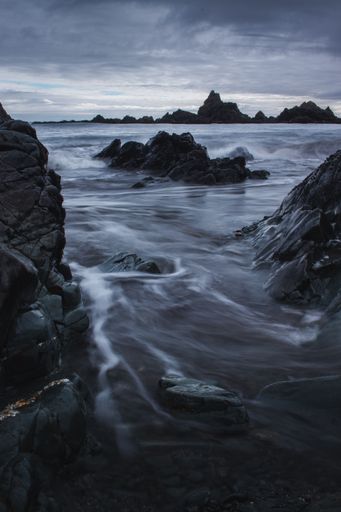 A vertical long exposure shot of a seashore with boulders