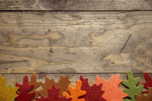 An overhead shot of a wooden surface with different color leaves on the bottom great for background