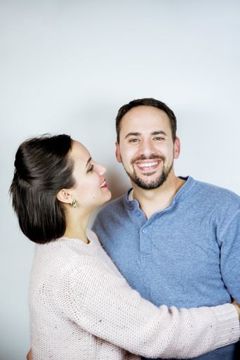 A vertical shot of a happy couple while she is looking at her boyfriend with a white background
