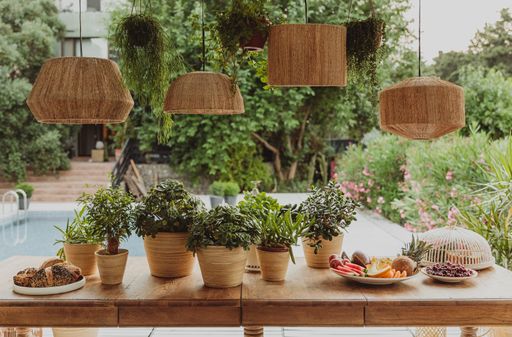 The decorative straw lamps over a wooden table with plant pots