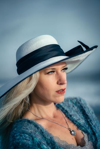 A beautiful woman wearing a summer hat with blue eyes and blonde hair