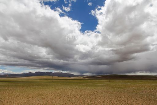 A beautiful view of a green field under cumulus clouds