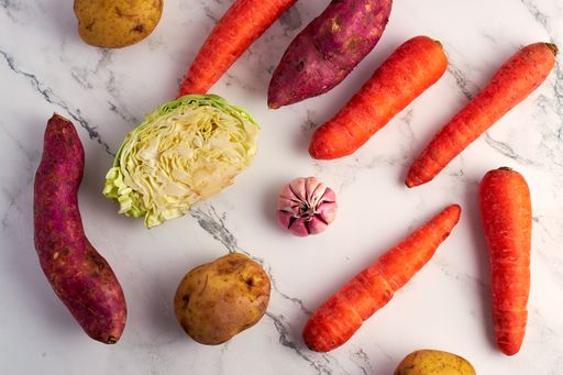 An overhead shot of different vegetables on a marble kitchen table surface