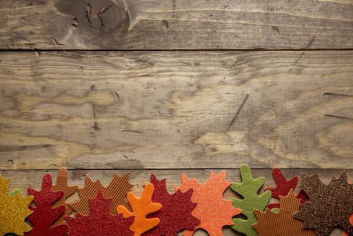 An overhead shot of a wooden surface with leaves cut out on the bottom great for background or writing a text