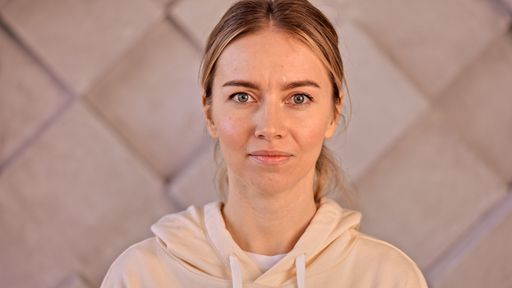A Caucasian woman with blonde hair and green eyes looking at camera