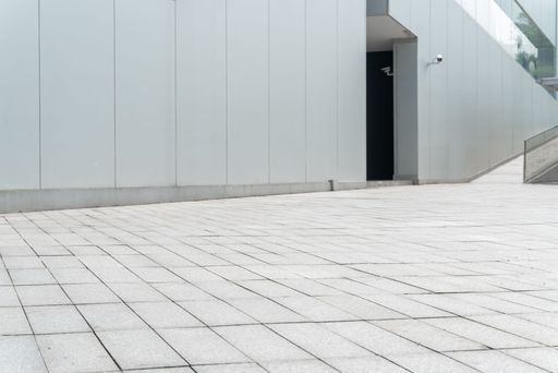 A closeup of bright stone tiles in front of modern architecture exterior