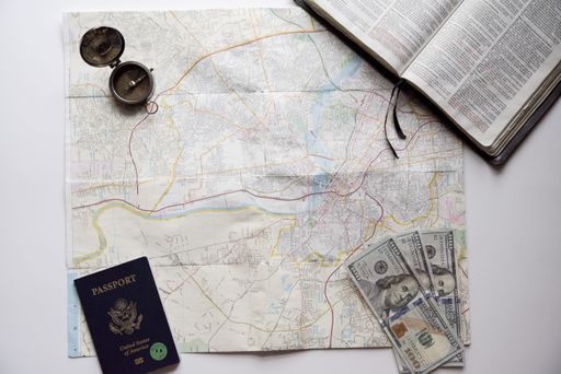 An overhead shot of a map in the middle of dollar bills, passport and a compass - concept for traveling