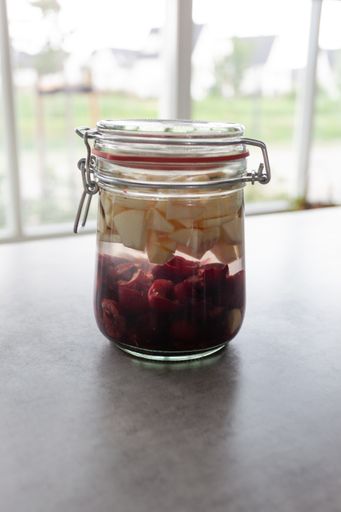A closeup shot of a glass bank with cut fruits on a grey table