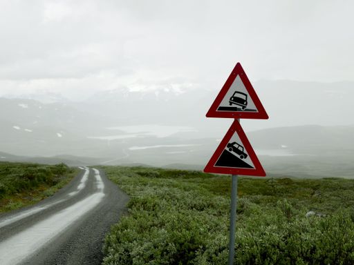 A closeup shot of dangerous roadside and steep descent road signs