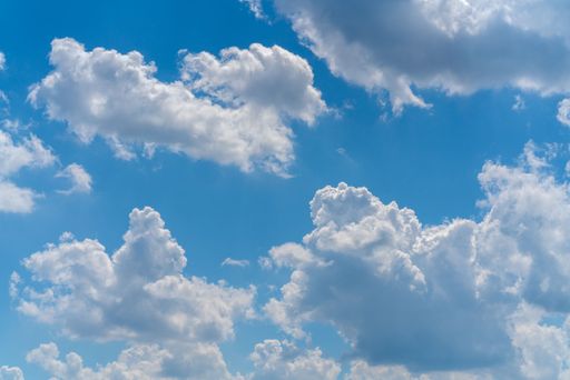 A scenic view of fluffy clouds in the blue sky during daytime