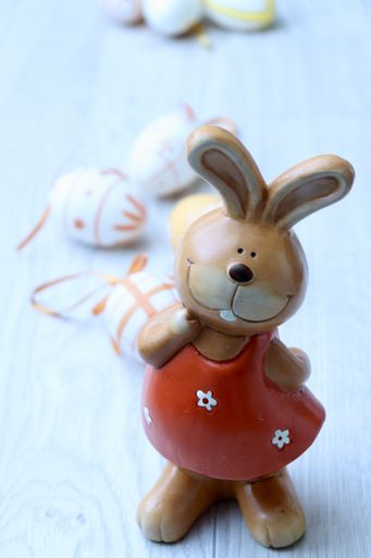 A vertical shot of an easter bunny figurine wearing a red dress on a wooden surface