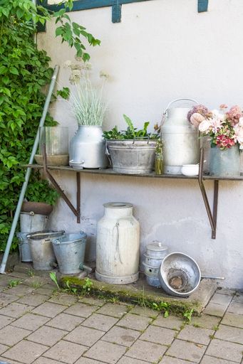 A vertical shot of rural floral decoration in pots and troughs on house wall for pleasant ambience