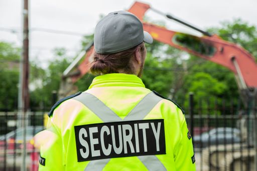 A closeup back shot of a security guard patrolling the street next to the construction area