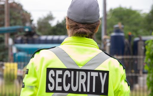 A closeup back shot of a security guard patrolling the street next to the construction area