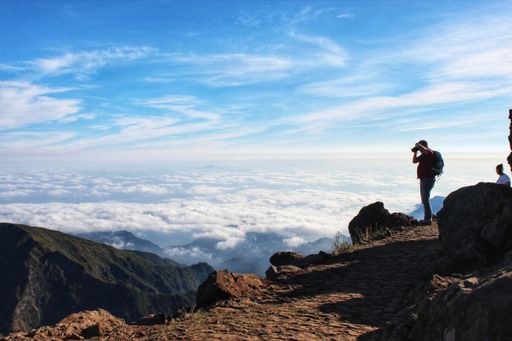 A side view of a man taking a photo standing on high mountains in Madeira, Portugal