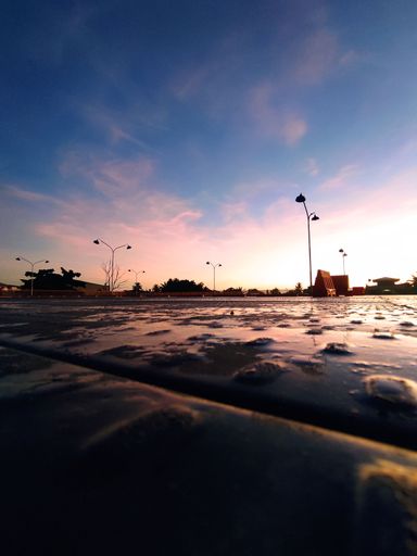 A vertical shot of a bright sunset sky over parking spaces near a mall
