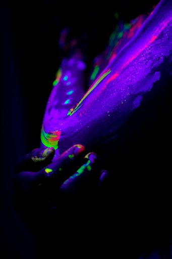 A vertical shot of a woman in ultraviolet body painting