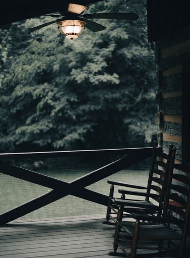 A cozy balcony with rocking chairs near green trees