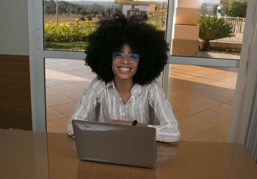 Attractive young woman indoors at home working doing home office on her laptop computer and mobile phone
