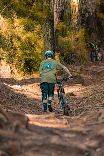 A man pushing his bicycle in the forest