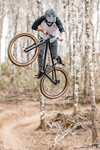 A man performing bicycle stunts in the forest