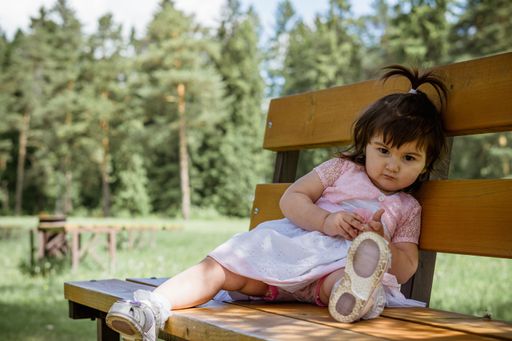 A close up of a little 2 year old girl in a park near a forest
