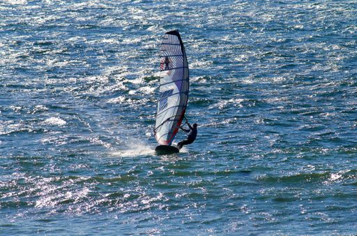 A person on a sailboat in teh sea on a sunny day