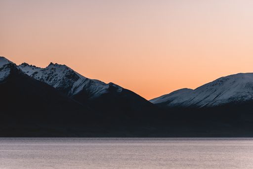 A beautiful view of the mountain near the lake pink sky behind