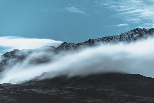A picturesque winter landscape featuring a snow-capped mountain surrounded by fluffy clouds